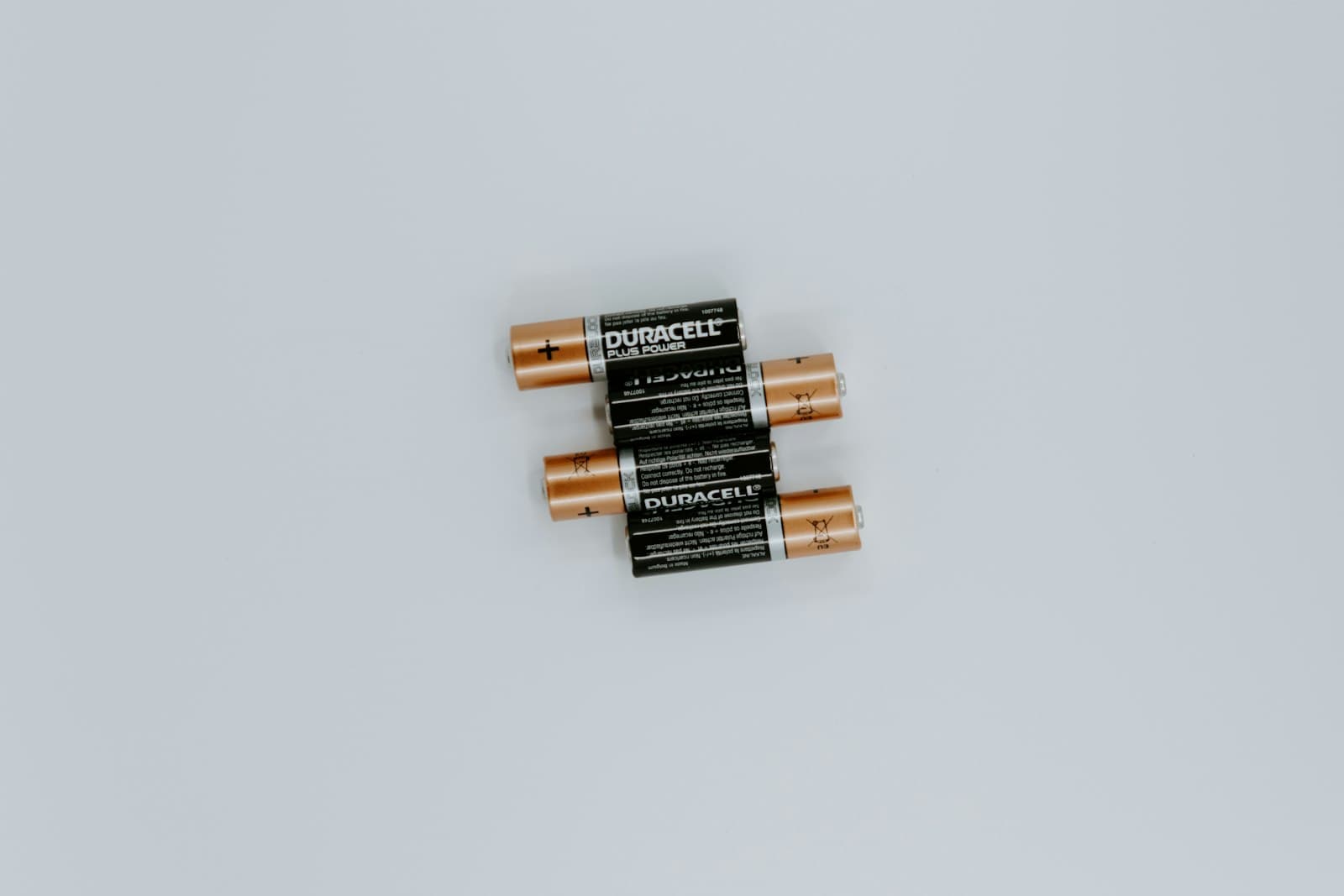 Four cylindrical rechargeable battery cells with black wrap standing upright on a plain surface