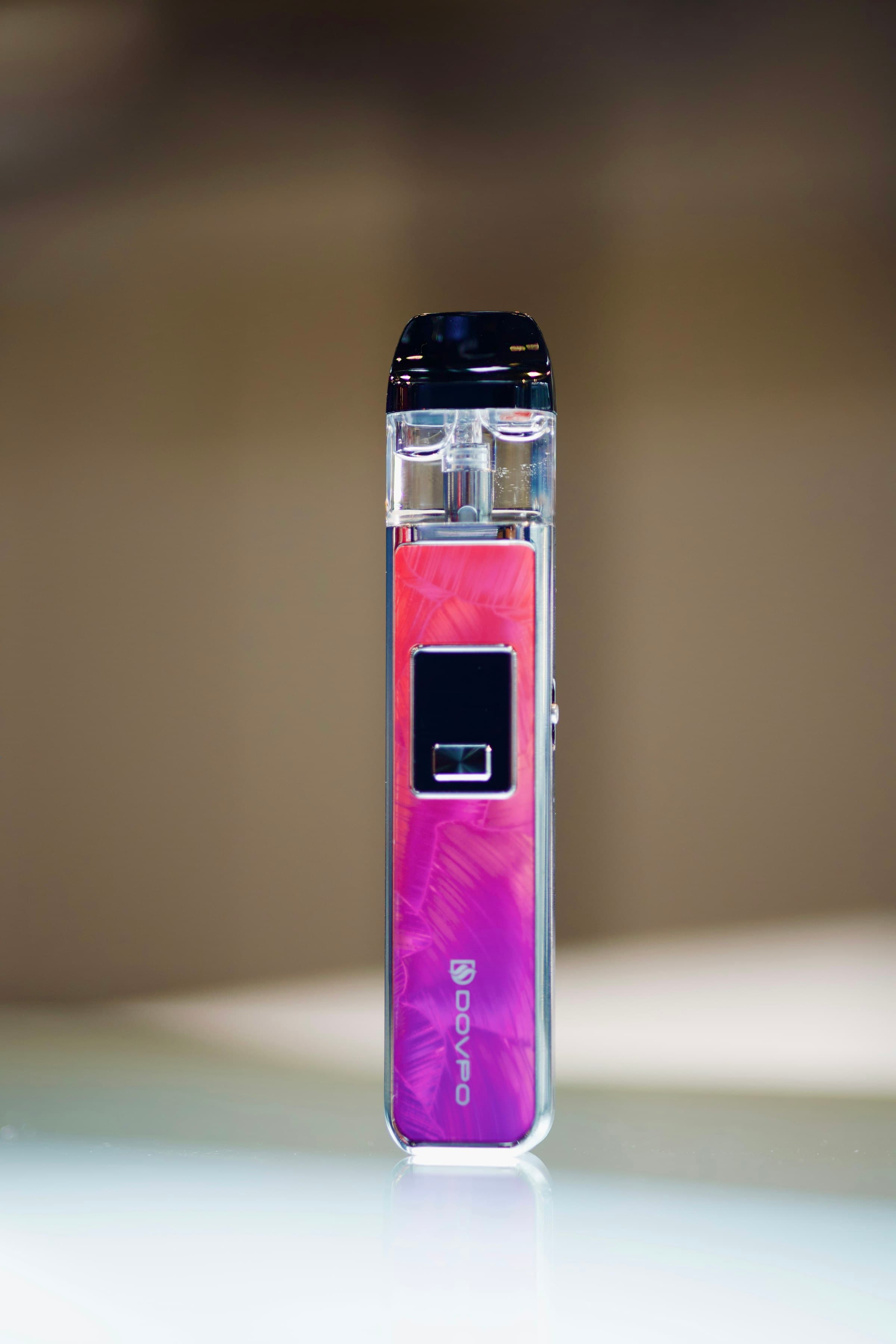 A rechargeable pod vape kit with coloured accent lighting sitting on a table surface