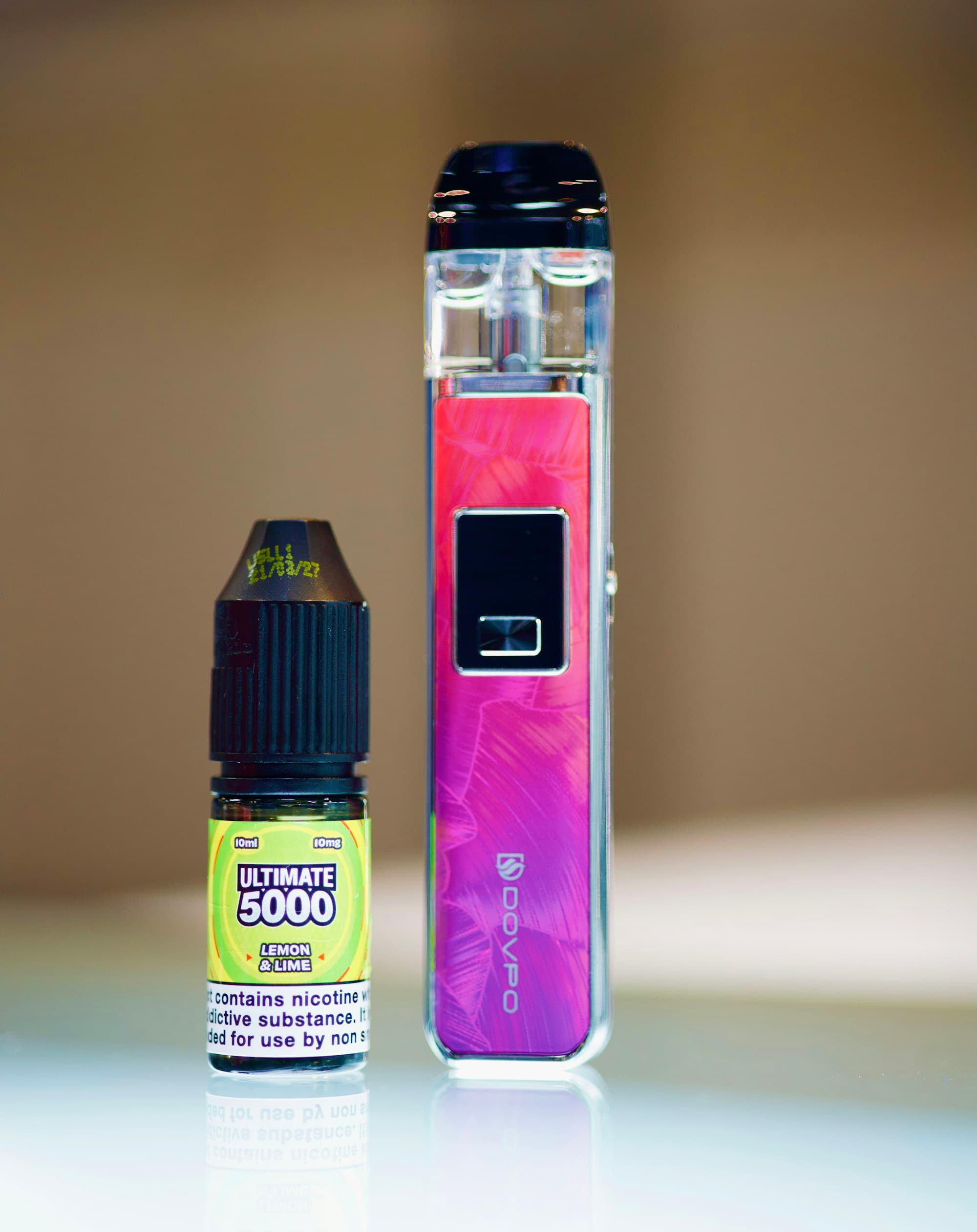 A small 10ml nicotine salt e-liquid bottle standing beside a compact pod vape device on a plain surface